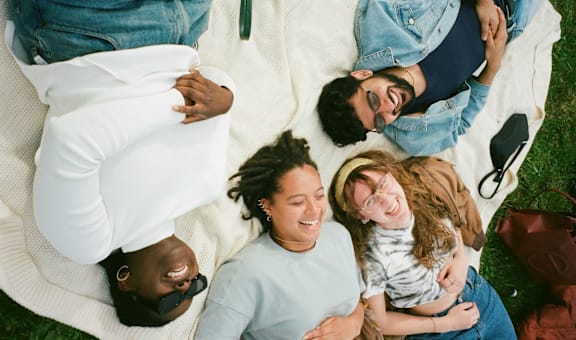 a group of people laying on a blanket on the grass