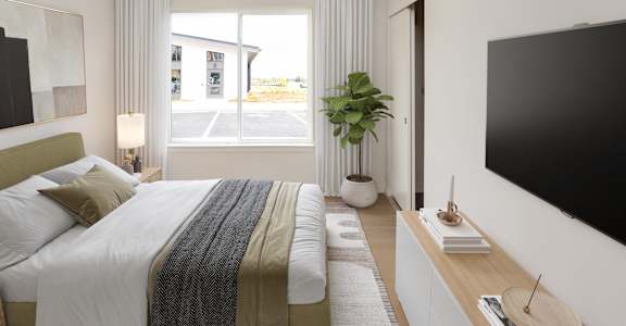 A bedroom with a large bed and a flat screen TV on the wall.