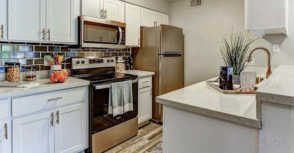 A kitchen with white cabinets and a stainless steel refrigerator.
