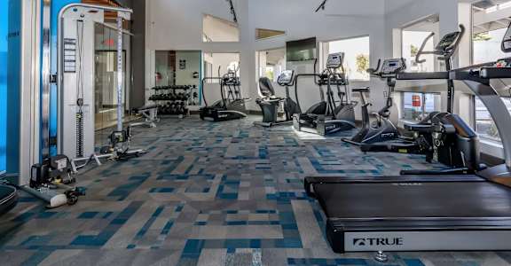 A gym with a variety of equipment including treadmills, weights, and exercise machines.