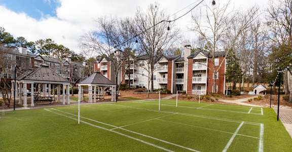 A tennis court is surrounded by buildings and trees.