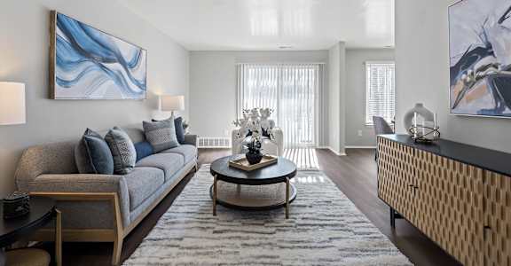 A living room with a grey couch, a coffee table, and a painting on the wall.