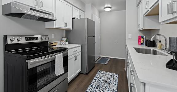 A modern kitchen with a black stove top oven and white cabinets.