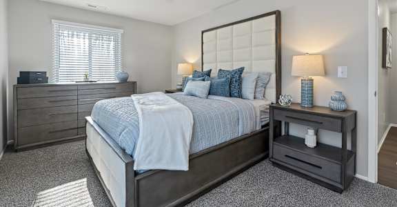 A bedroom with a bed, nightstand, and lamp.