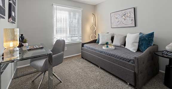 A grey bedroom with a bed, desk, and chair.