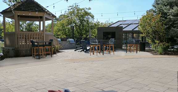 A gazebo is surrounded by a patio with a table and chairs.