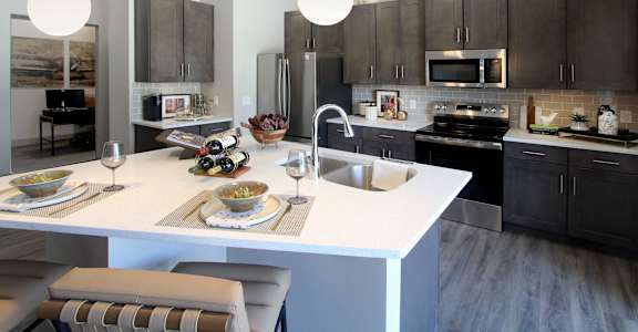 A modern kitchen with a white island and black cabinets.