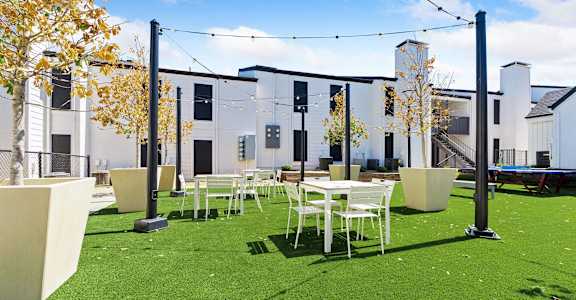 a courtyard with tables and chairs and a building in the background