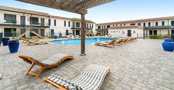 a resort style pool with lounge chairs and a pergola