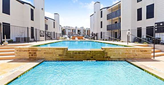 a large swimming pool with apartments in the background