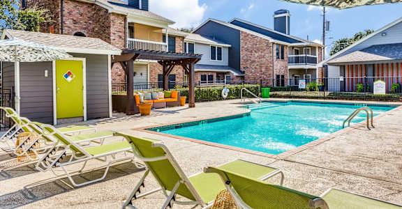 A pool area with sun loungers and a yellow door.