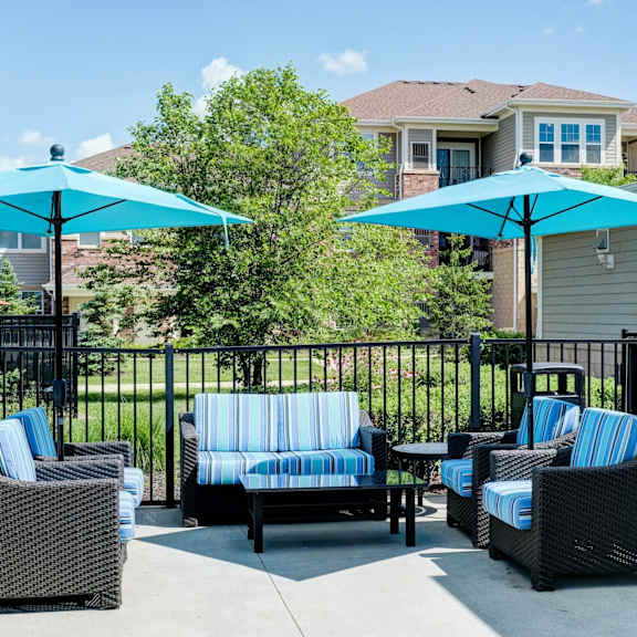 Four people are sitting on a patio with blue umbrellas.