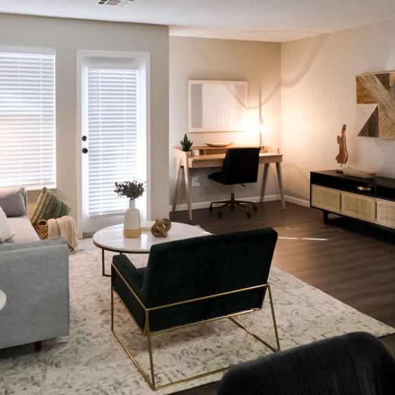 a living room with a desk in the background and a couch in the foreground