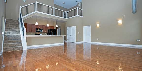 A shiny air hockey table is in the middle of a room with chairs and a kitchen in the background.
