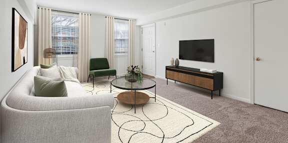 A living room with a grey couch, a green chair, a coffee table, and a television.