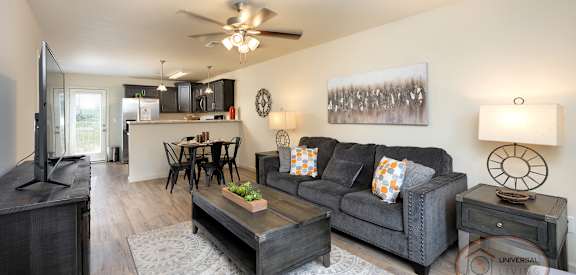 A living room with a grey couch, a coffee table, and a ceiling fan.