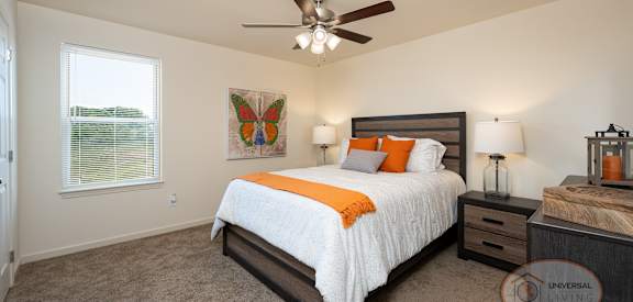 A bedroom with a bed, nightstand, and a ceiling fan.