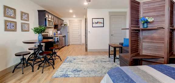 A bedroom with a bed, a dining table, and a ceiling fan.