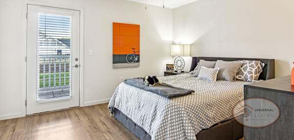 A bedroom with a bed, a ceiling fan, and a painting on the wall.