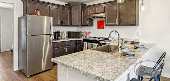 A kitchen with a marble counter top and a stainless steel refrigerator.