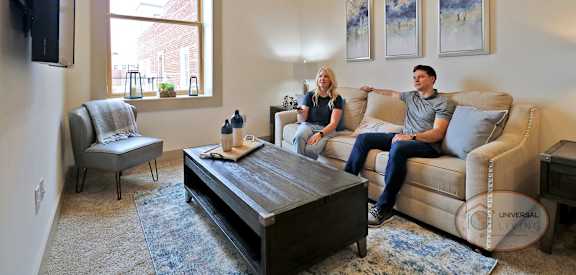 Three people are sitting on a couch in a living room.