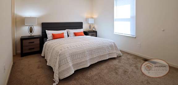A bedroom with a bed, nightstand, and window.