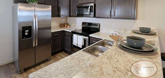 A kitchen with a refrigerator, microwave, oven, and sink.