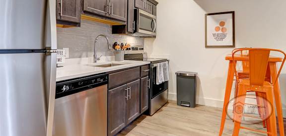 A kitchen with a refrigerator, sink, and orange chair.