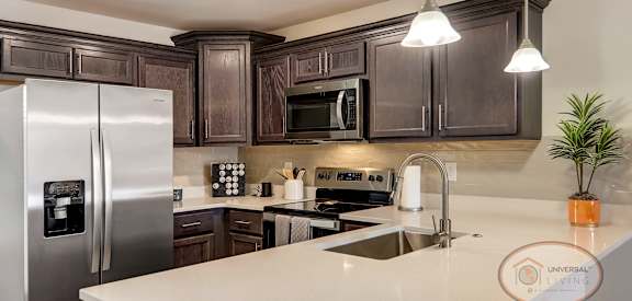 A modern kitchen with dark wood cabinets and stainless steel appliances.