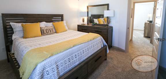 A bedroom with a bed, dresser, mirror, and ceiling fan.