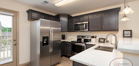 A kitchen with a stainless steel refrigerator, microwave, oven, and sink.