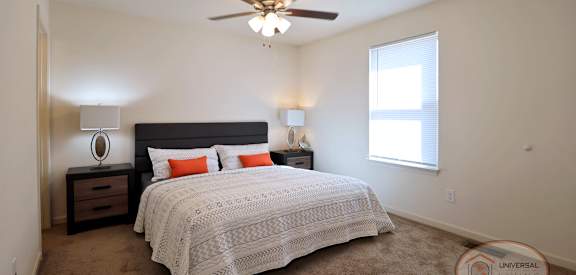 A bedroom with a bed, nightstand, and window.