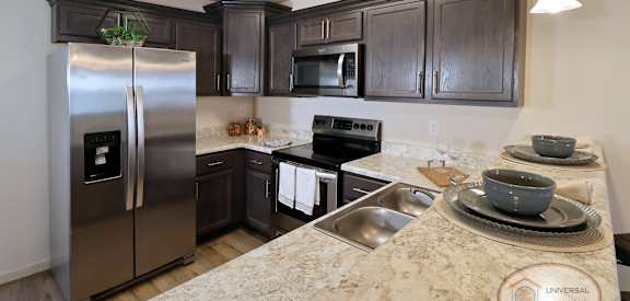 A kitchen with a refrigerator, microwave, oven, and sink.