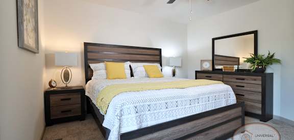 A bedroom with a bed, nightstand, and a ceiling fan.