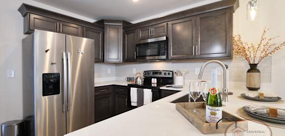 A kitchen with a stainless steel refrigerator and dark brown cabinets.