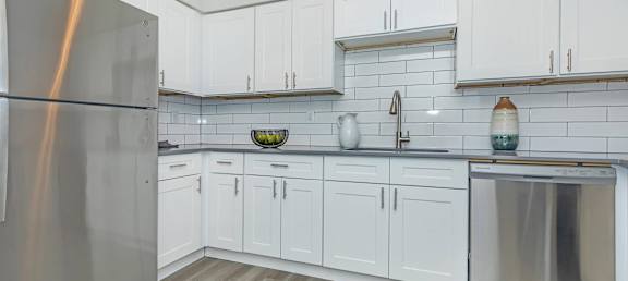 A kitchen with white cabinets and a stainless steel refrigerator.at Solara, Phoenix