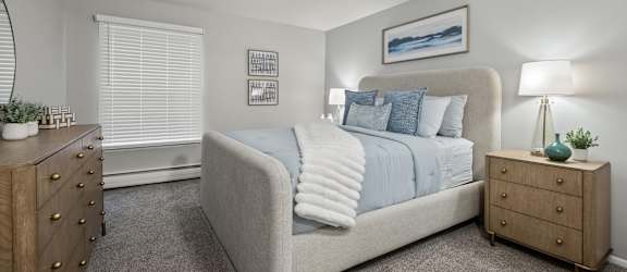 A bedroom with a bed, nightstand, and dresser.