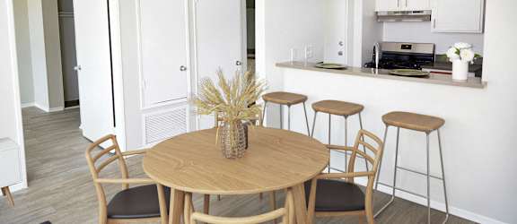 a dining room and kitchen looking into the kitchen with a table and stools