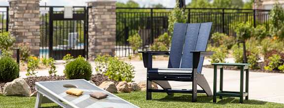 a lounge chair and a coffee table on a lawn in a backyard