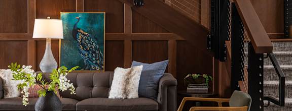 A living room with a brown couch, a round coffee table, and a staircase.