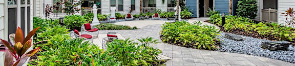 A courtyard with a white tile floor and a variety of plants and trees. at CODA Apartments , Florida, 32826