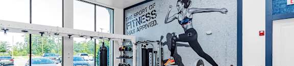 a fully equipped gym with a mural of a woman running on the wall at CODA Apartments , Florida, 32826