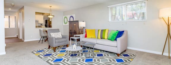 a living room with a grey couch and yellow and blue rug