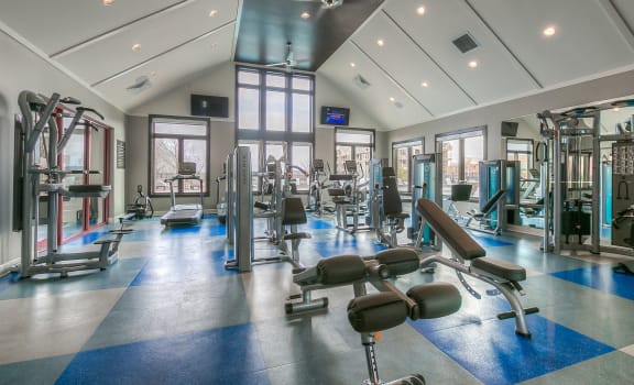 a gym with weights and cardio equipment on the floor and windows  at Waterside Residences on Quivira, Kansas, 66215