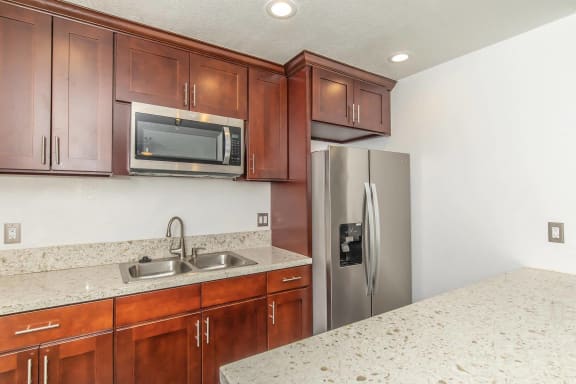 A kitchen with brown cabinets and a stainless steel refrigerator at Villa La Paz Apartments, California, 90706