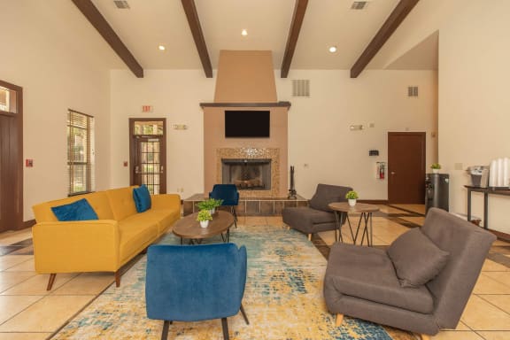 A living room with a yellow couch, blue chair, and a fireplace. at Lost Creek, San Antonio, TX