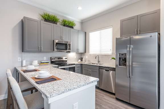 A kitchen with a granite countertop and stainless steel appliances.