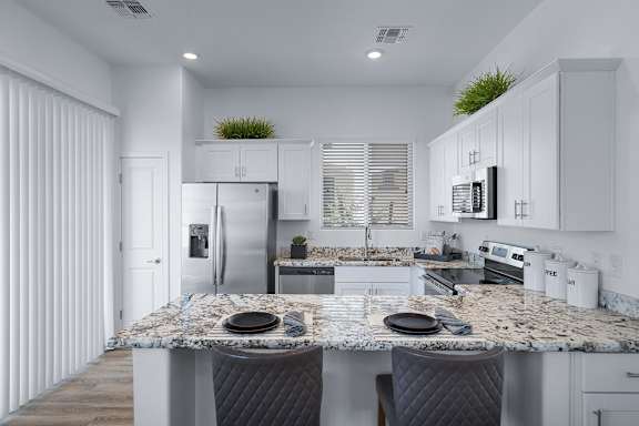A modern kitchen with granite countertops and white cabinets.
