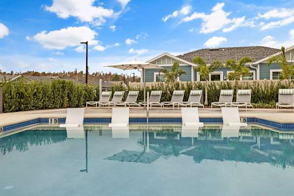 a swimming pool with lounge chairs and a house in the background