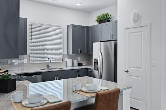 A modern kitchen with a dining table set for two.